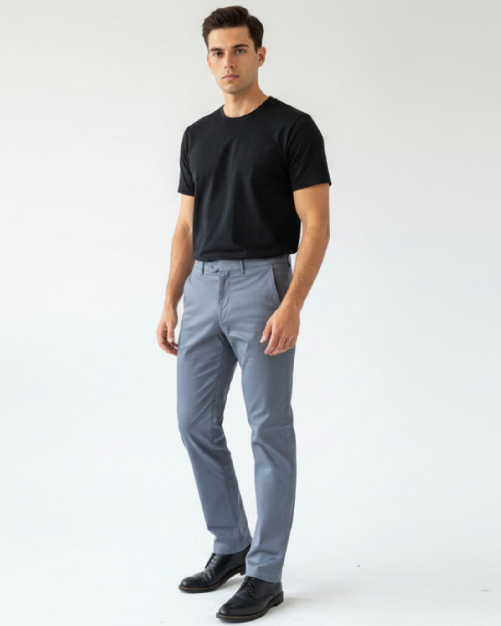 Man wearing a black t-shirt and light gray pants on a white background
