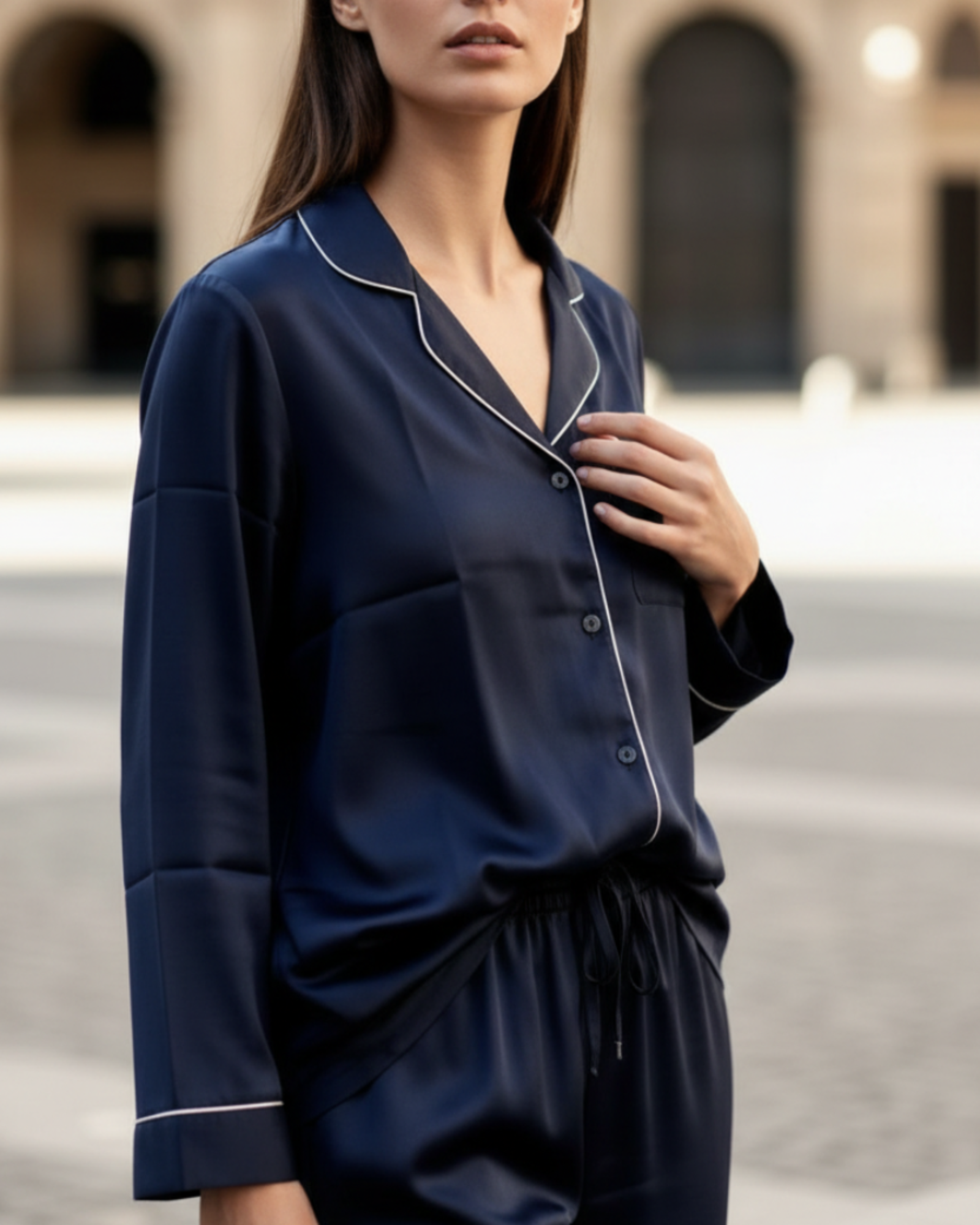 Woman wearing a navy blue pajama set with white piping in an outdoor setting.