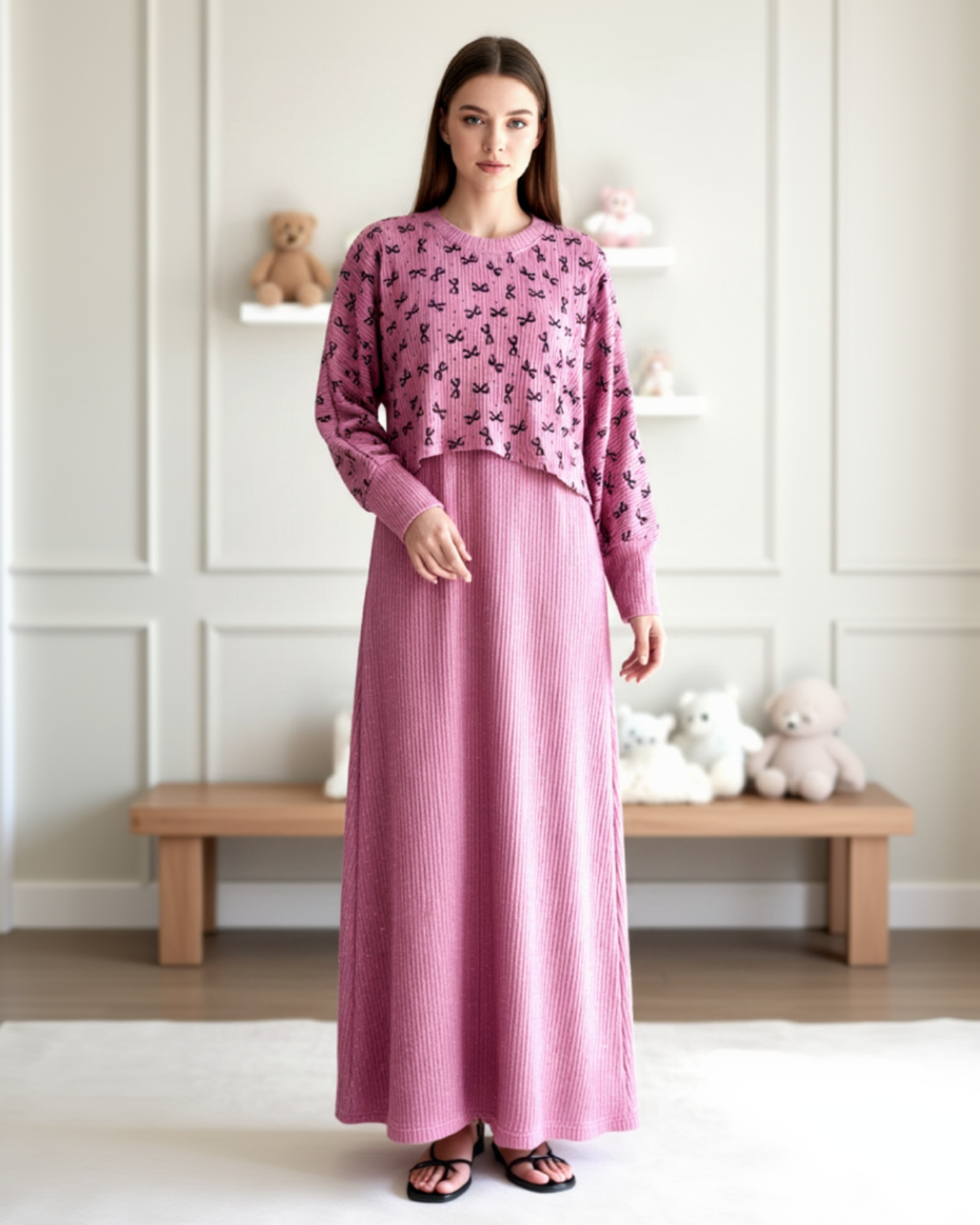 Woman wearing a pink outfit with a floral top and long skirt in a room setting.