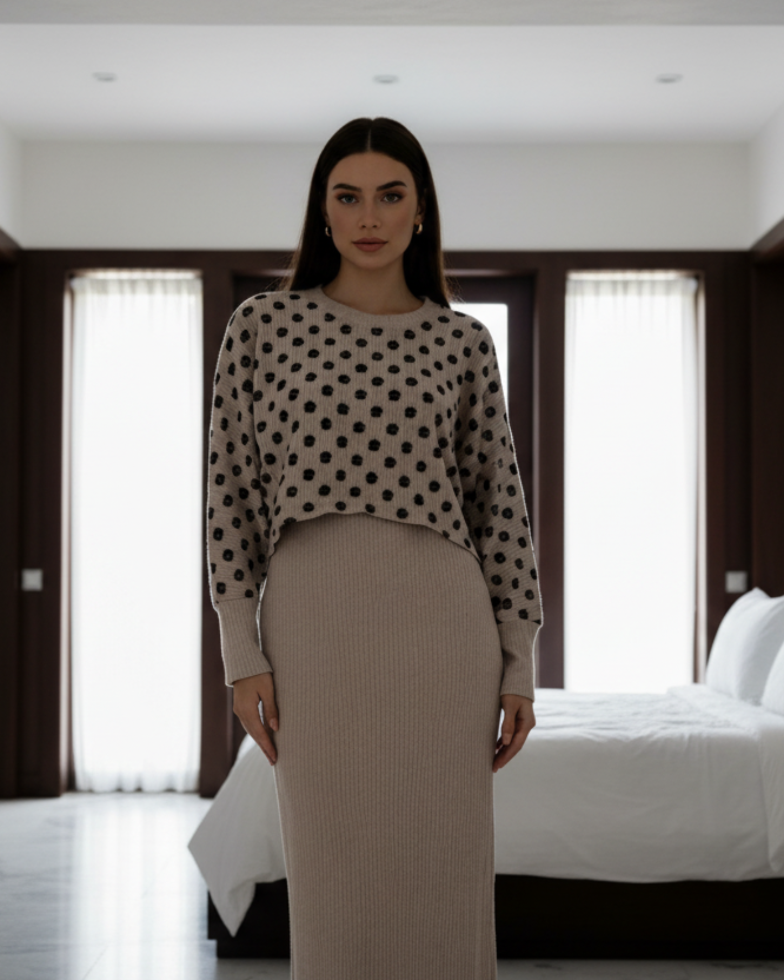 Woman wearing a polka dot blouse and beige skirt in a minimalistic setting