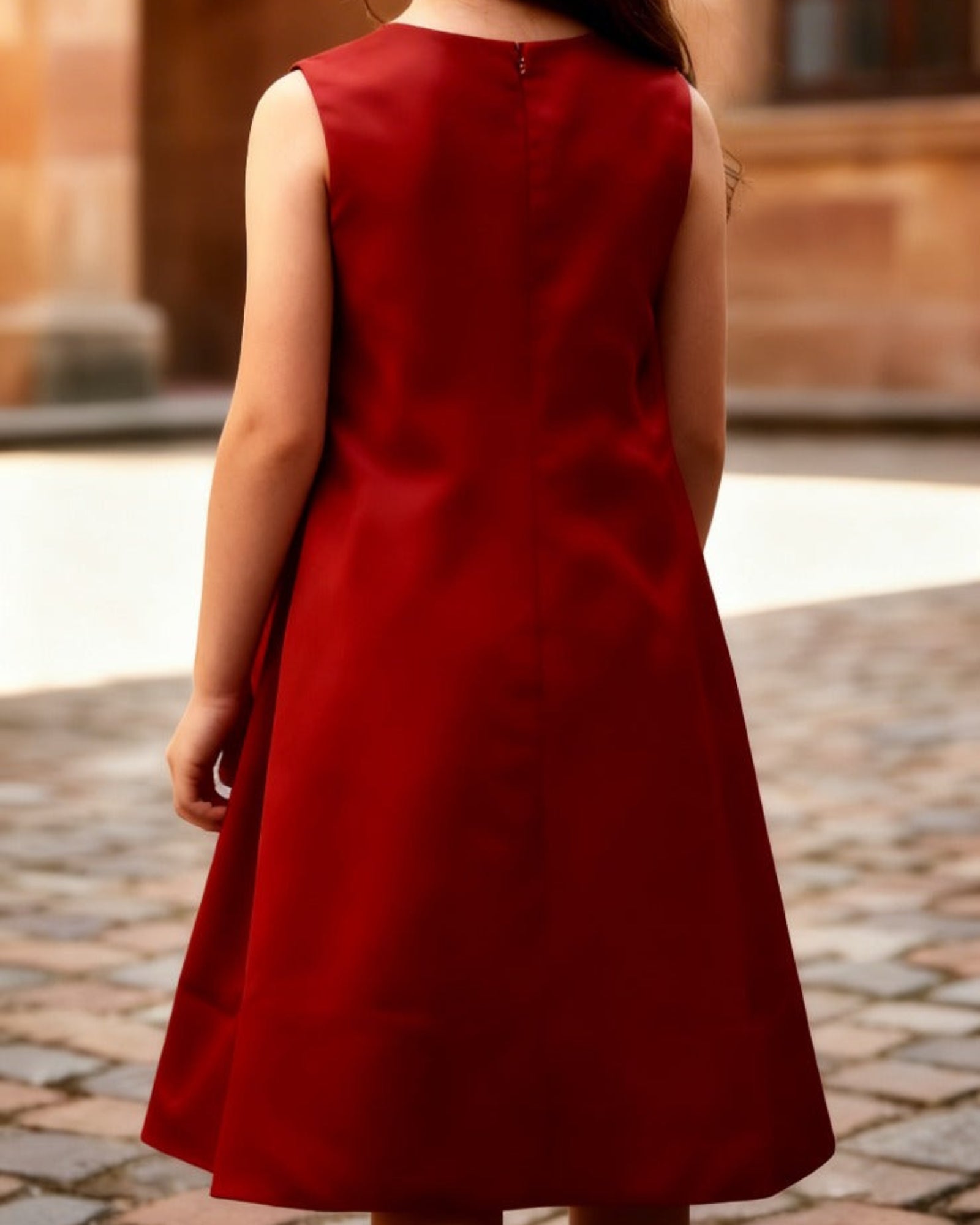Woman in a red dress standing in an outdoor setting with arches and lights.