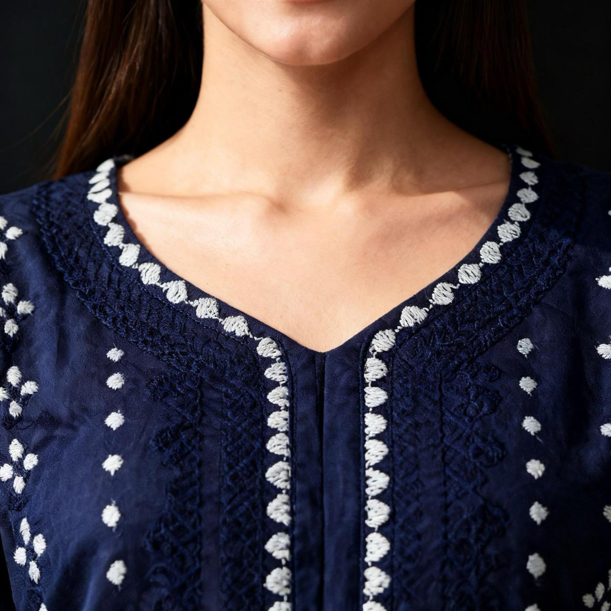 Navy blue blouse with white embroidery on a dark background