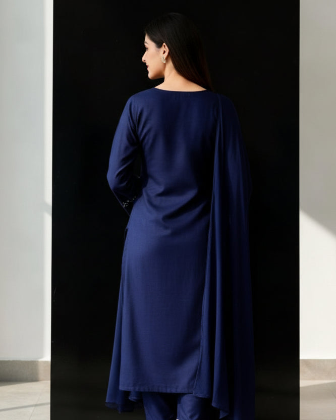Woman wearing a dark blue embroidered traditional outfit in a minimalistic setting