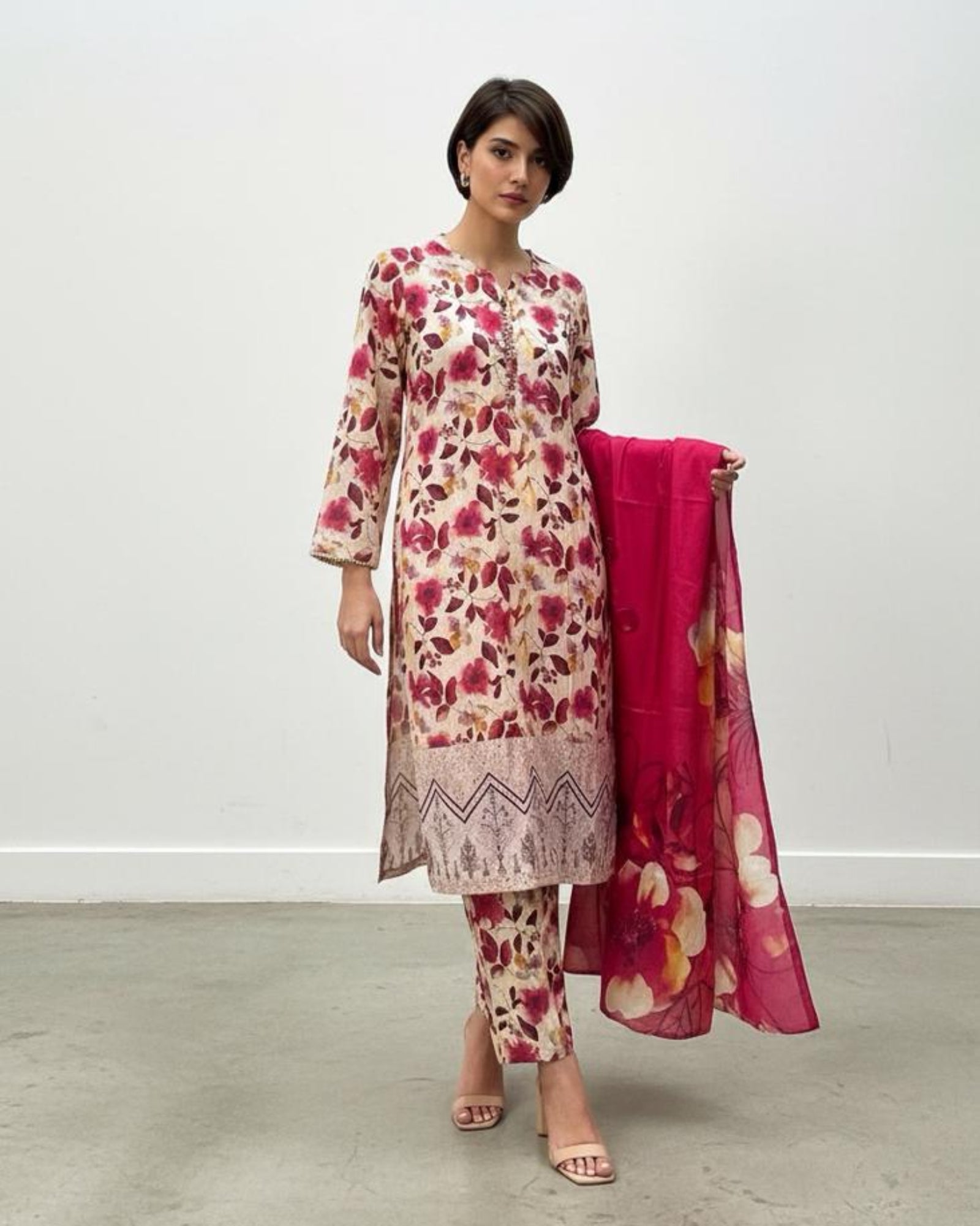 Woman wearing a floral dress with a pink dupatta on a white background