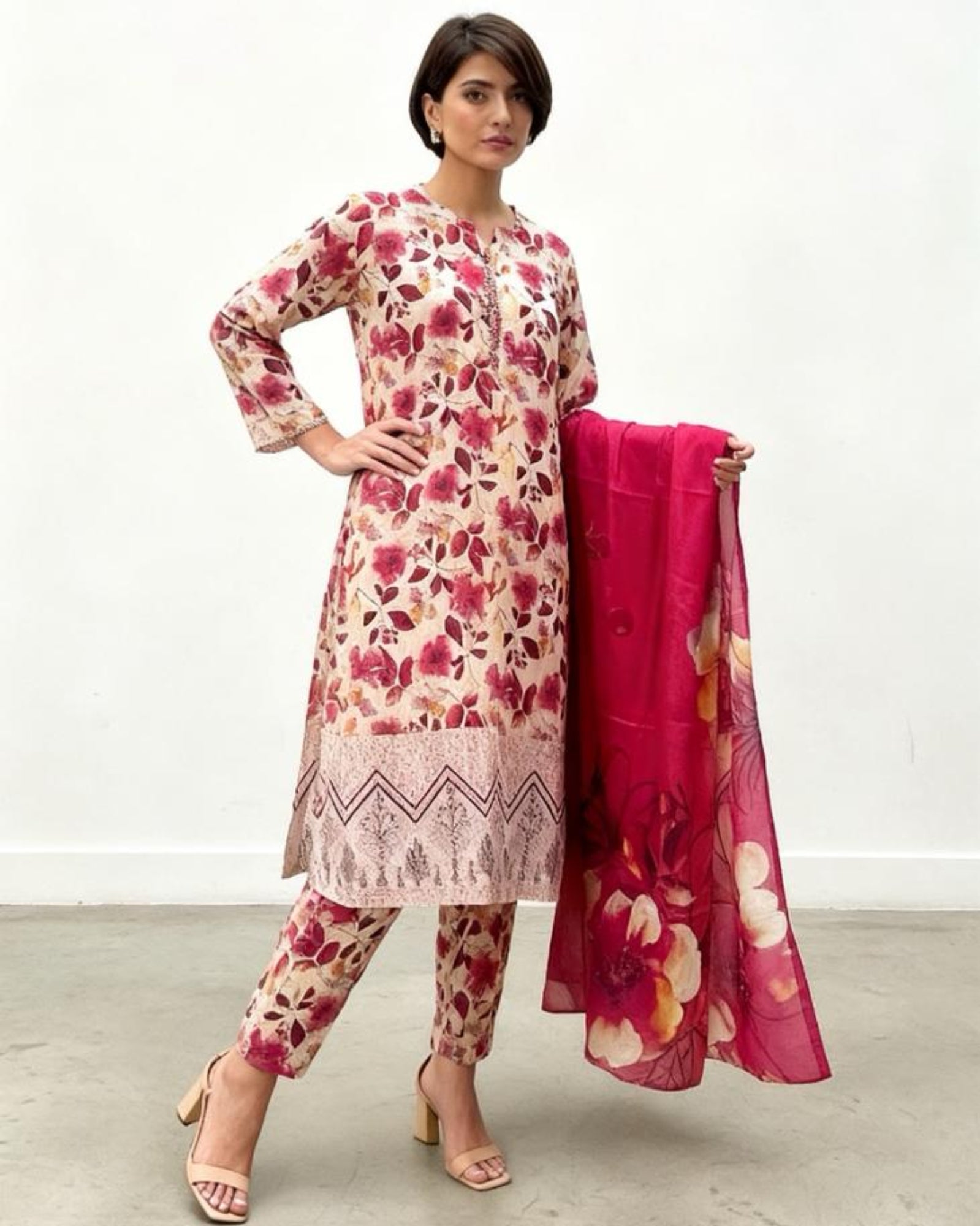 Woman wearing a floral dress and pants with a matching dupatta on a white background