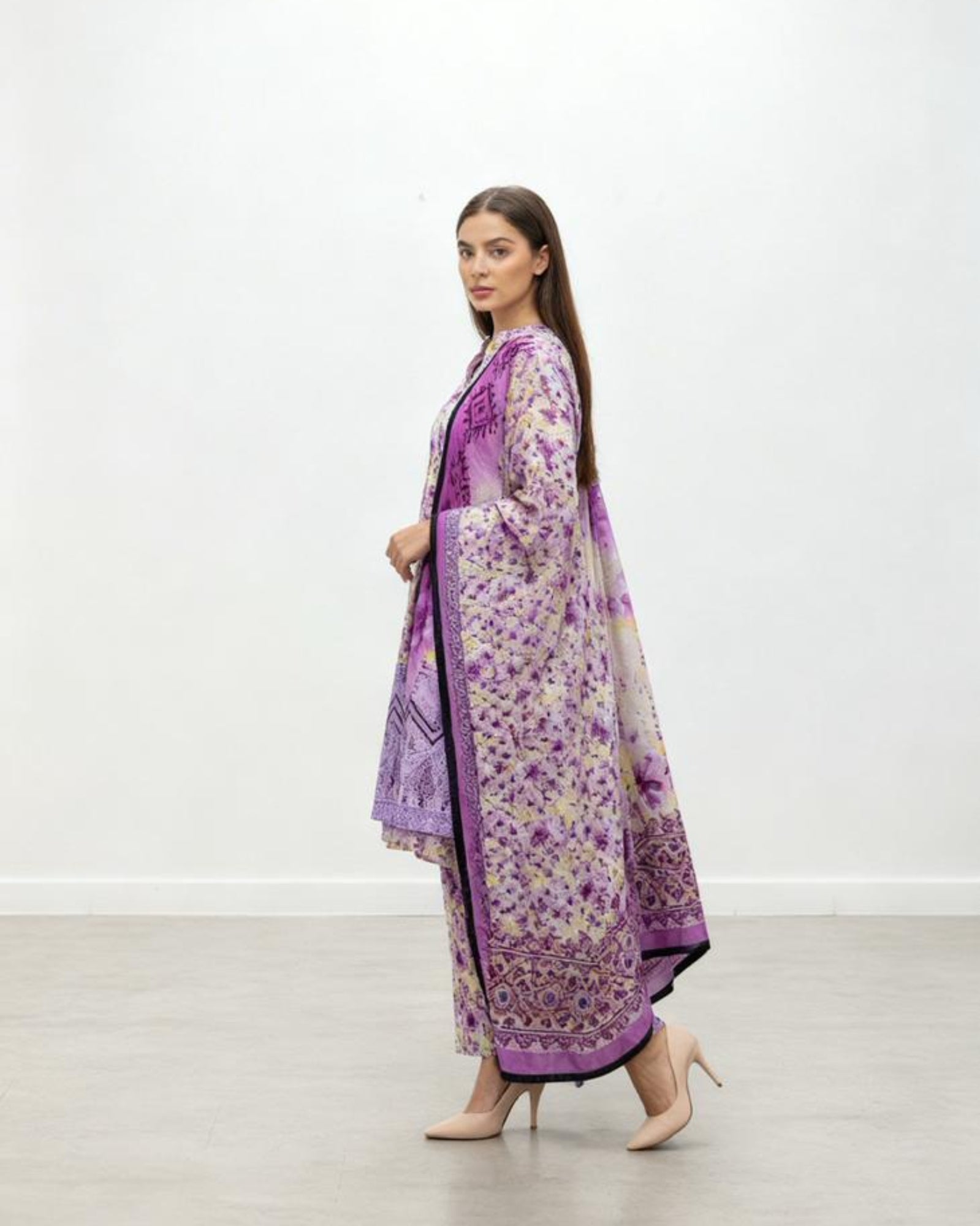 Woman wearing a purple floral dress in a minimal white room