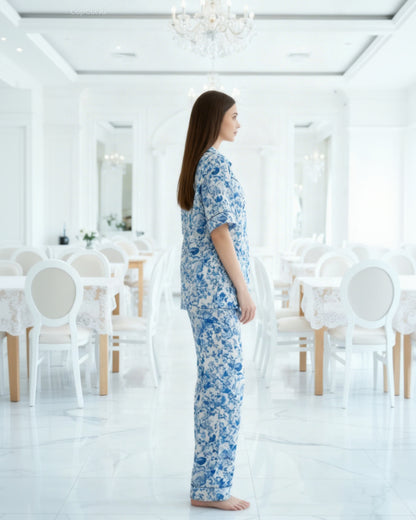 Woman wearing a blue floral pajama set in a white room with chairs and tables.