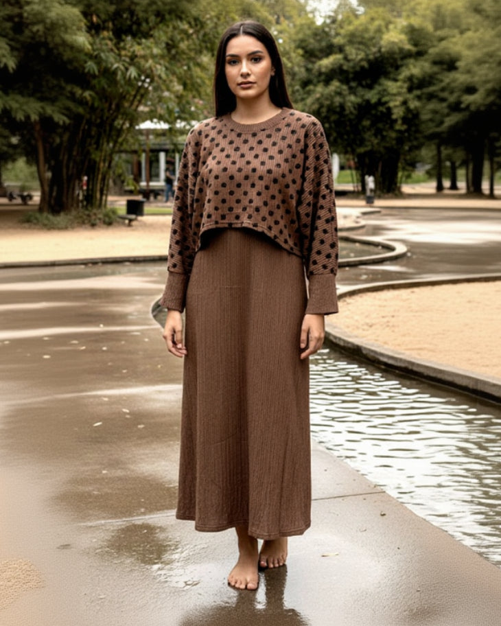 A woman stands barefoot on a wet park pathway, wearing the Luna Grace Maxi Dress with a patterned sweater. Trees and greenery are visible in the background.