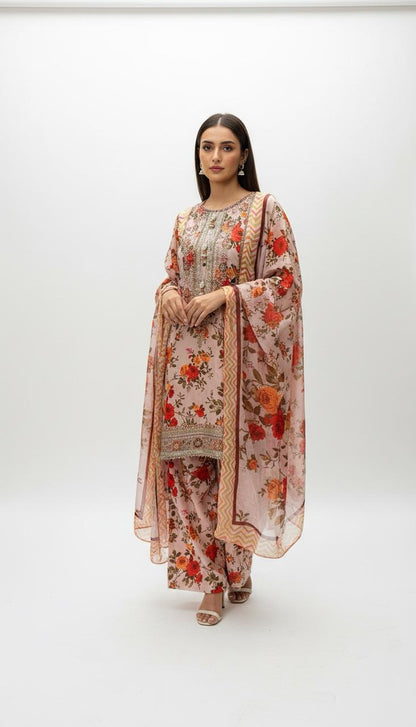 A woman stands against a white backdrop wearing the Refined Embroidered Suit—a floral printed outfit with delicate embroidery, matching dupatta and pants. With straight hair, minimal jewelry, and sandals, it’s ideal for festive daytime occasions.