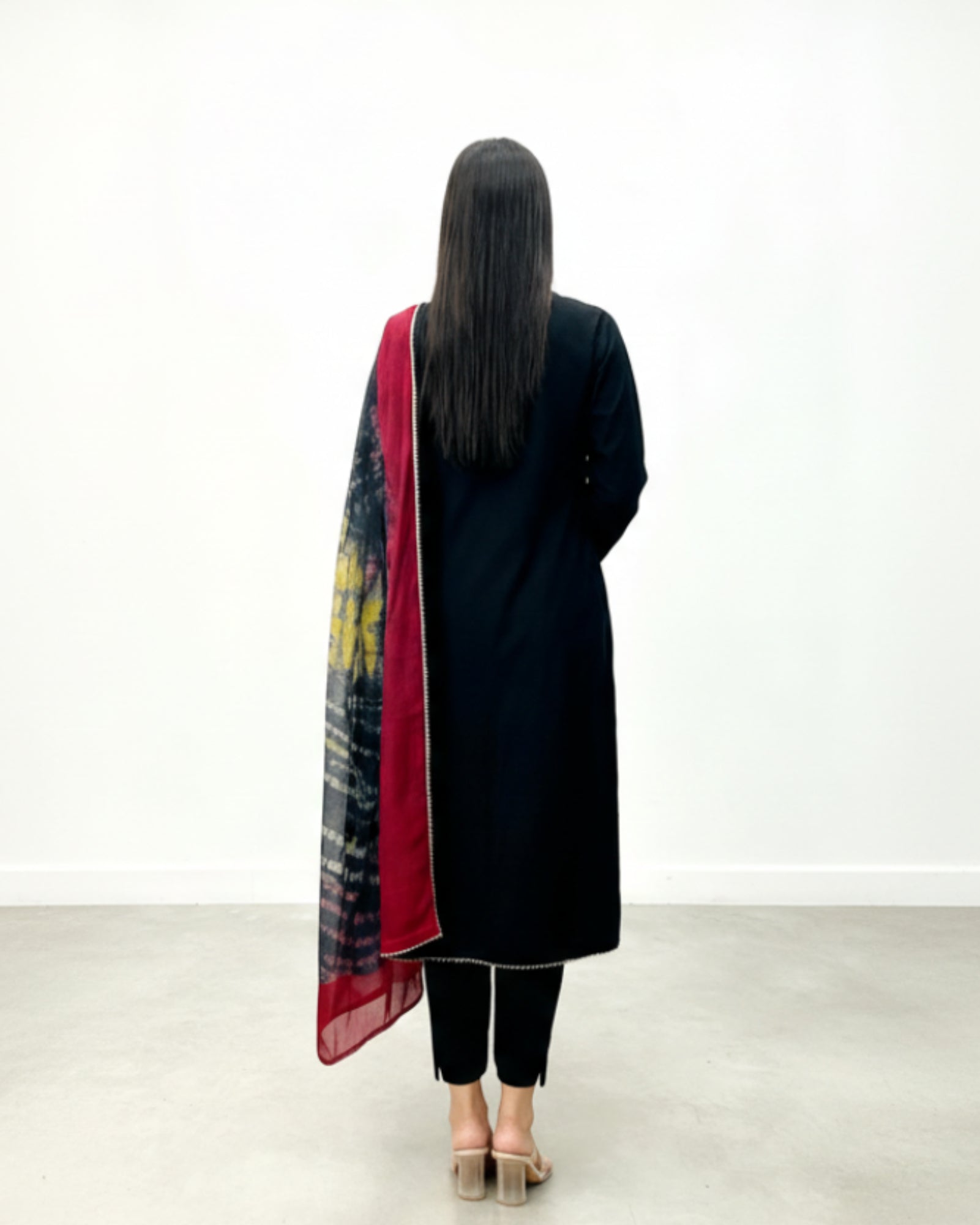 Person wearing a black coat and red scarf with a white background