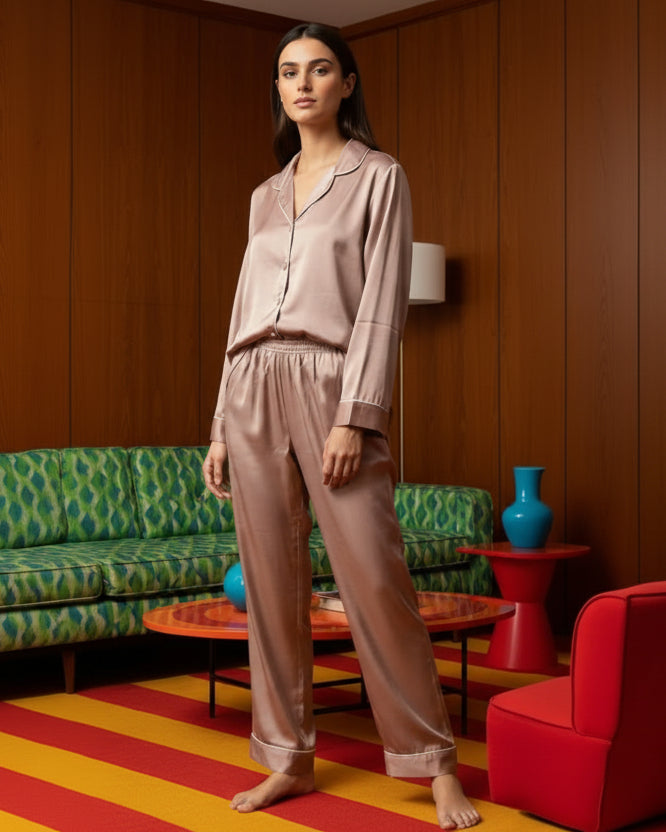 Woman in a beige satin pajama set standing in a room with colorful decor.