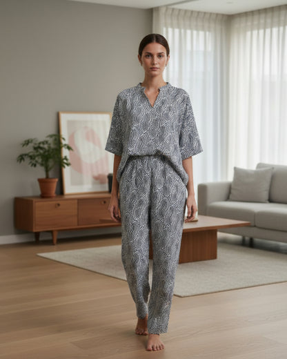 Woman in a patterned outfit standing in a modern living room.