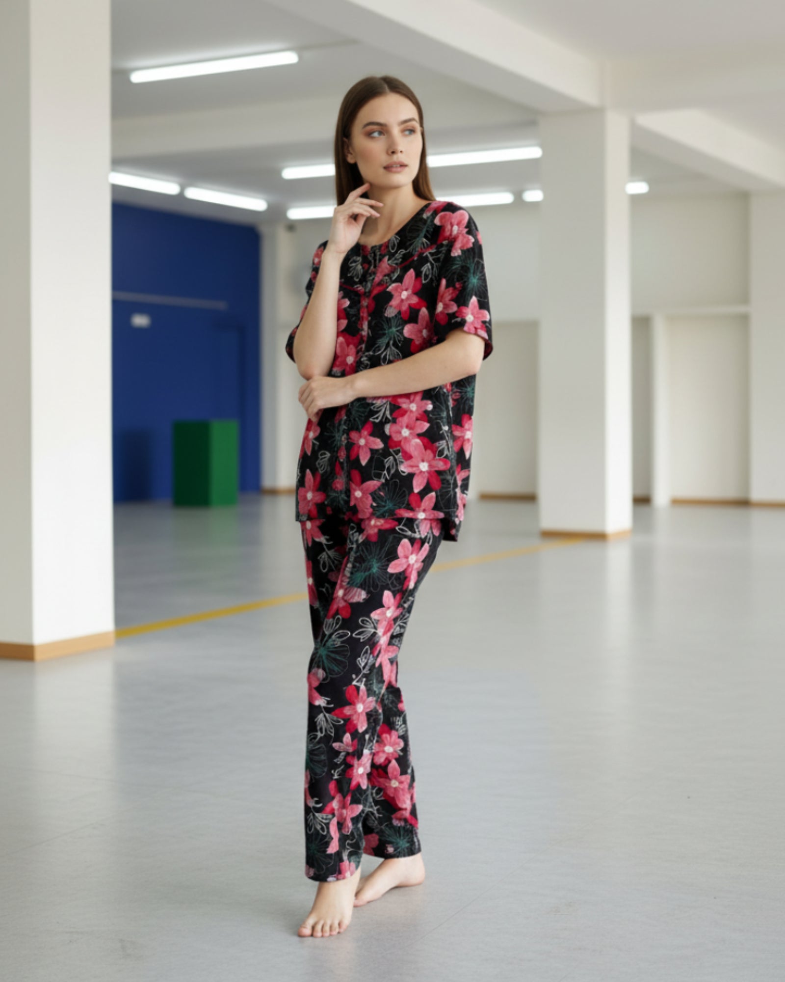 Woman wearing a black floral pajama set in a large indoor space with high ceilings.