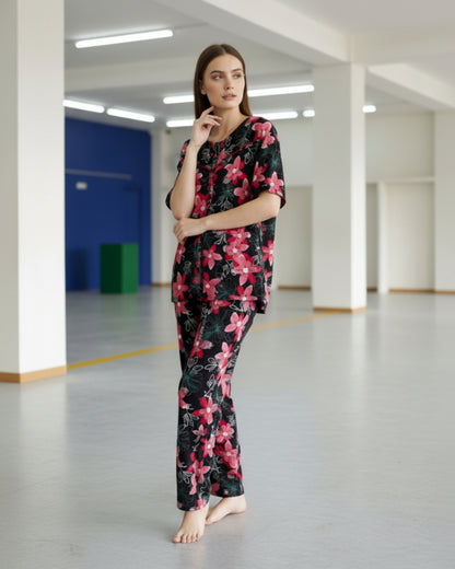 Woman wearing a black floral pajama set in a large indoor space with high ceilings.