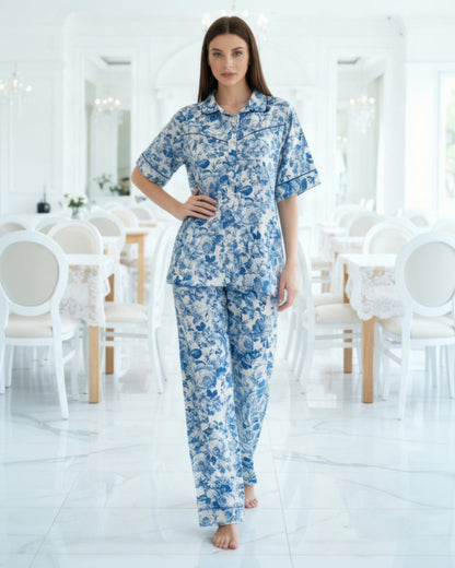 Woman wearing a blue floral pajama set in a bright, minimalistic room.
