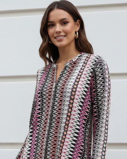 Woman wearing a patterned outfit standing against a light-colored wall.