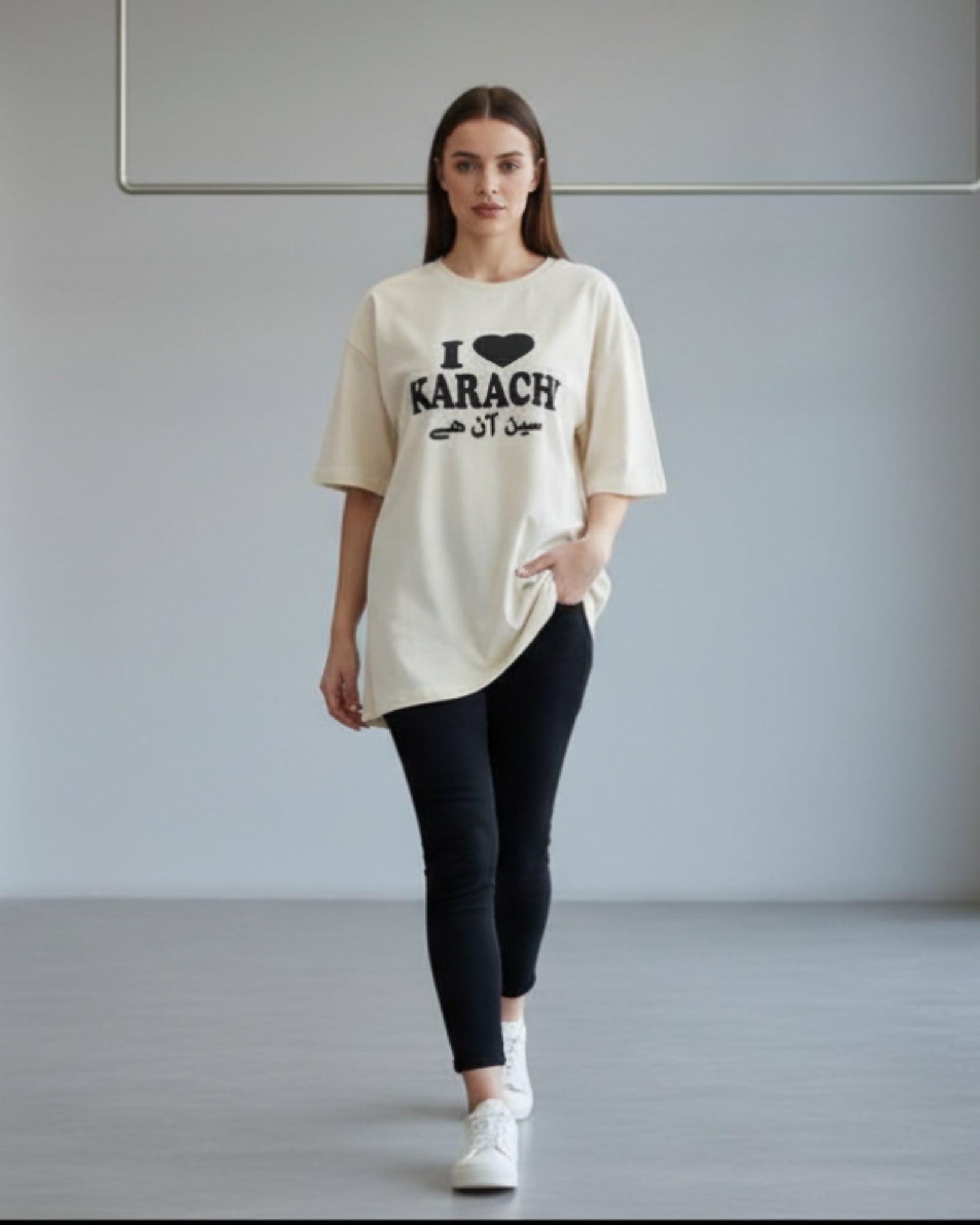 Woman wearing a white t-shirt with text, standing in a minimalistic room.