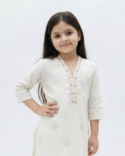 Young girl wearing a white kurta with floral patterns on a light gray background