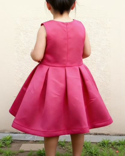 Child wearing a bright pink dress against a light background