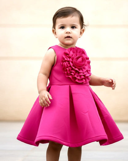 Child wearing a bright pink dress with floral details against a neutral background