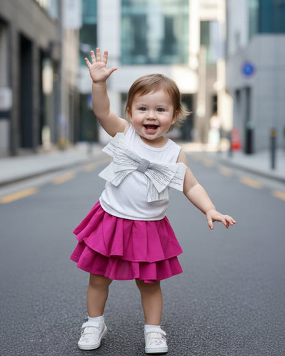 Child wearing a white top with ruffles and a pink skirt on a city street.