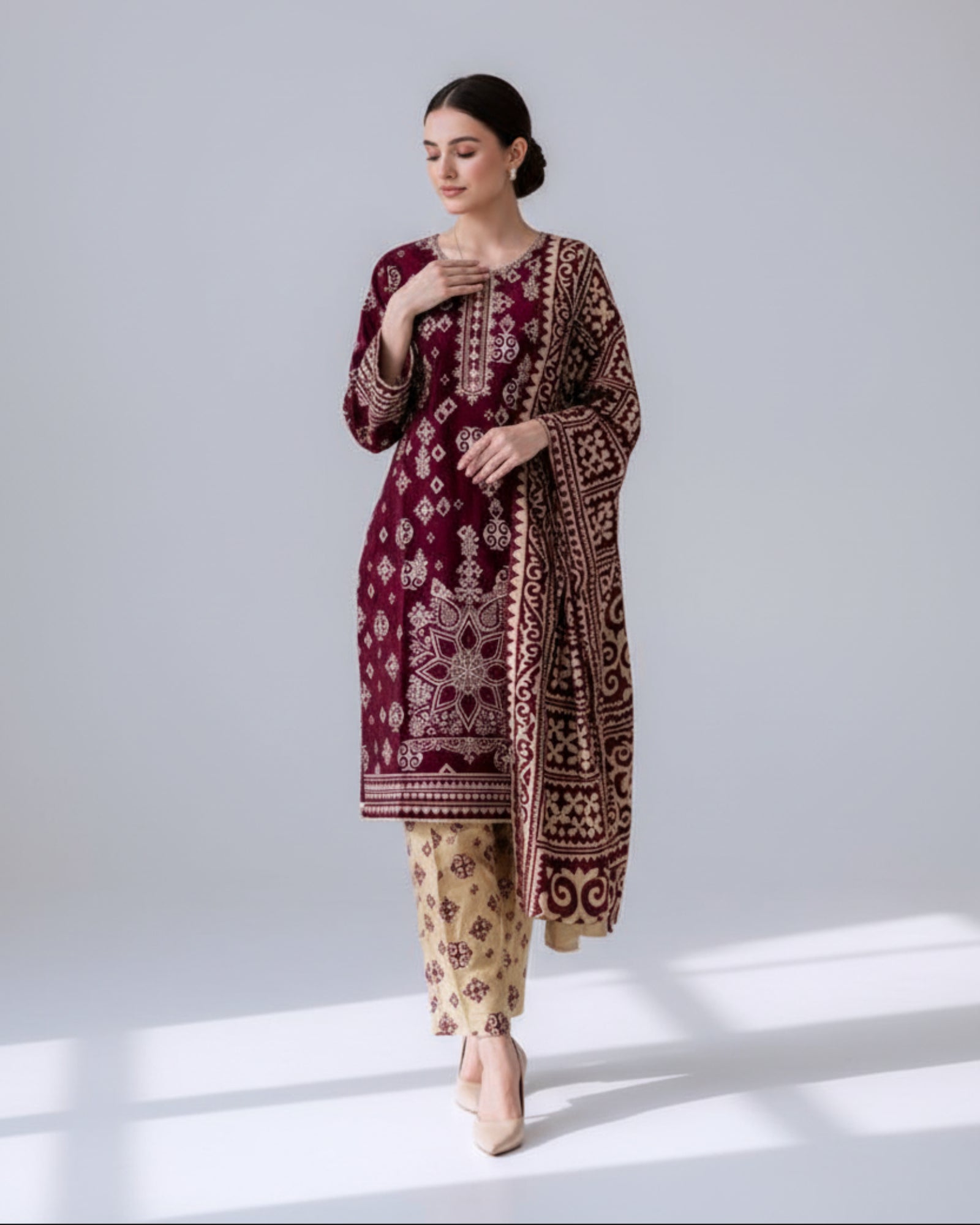 Woman wearing a maroon embroidered outfit with beige pants in front of a mirror.