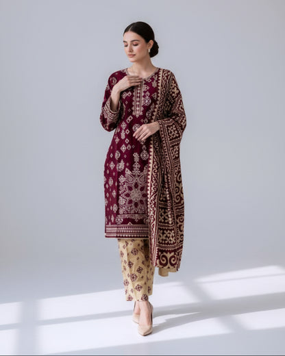 Woman wearing a maroon embroidered outfit with beige pants in front of a mirror.