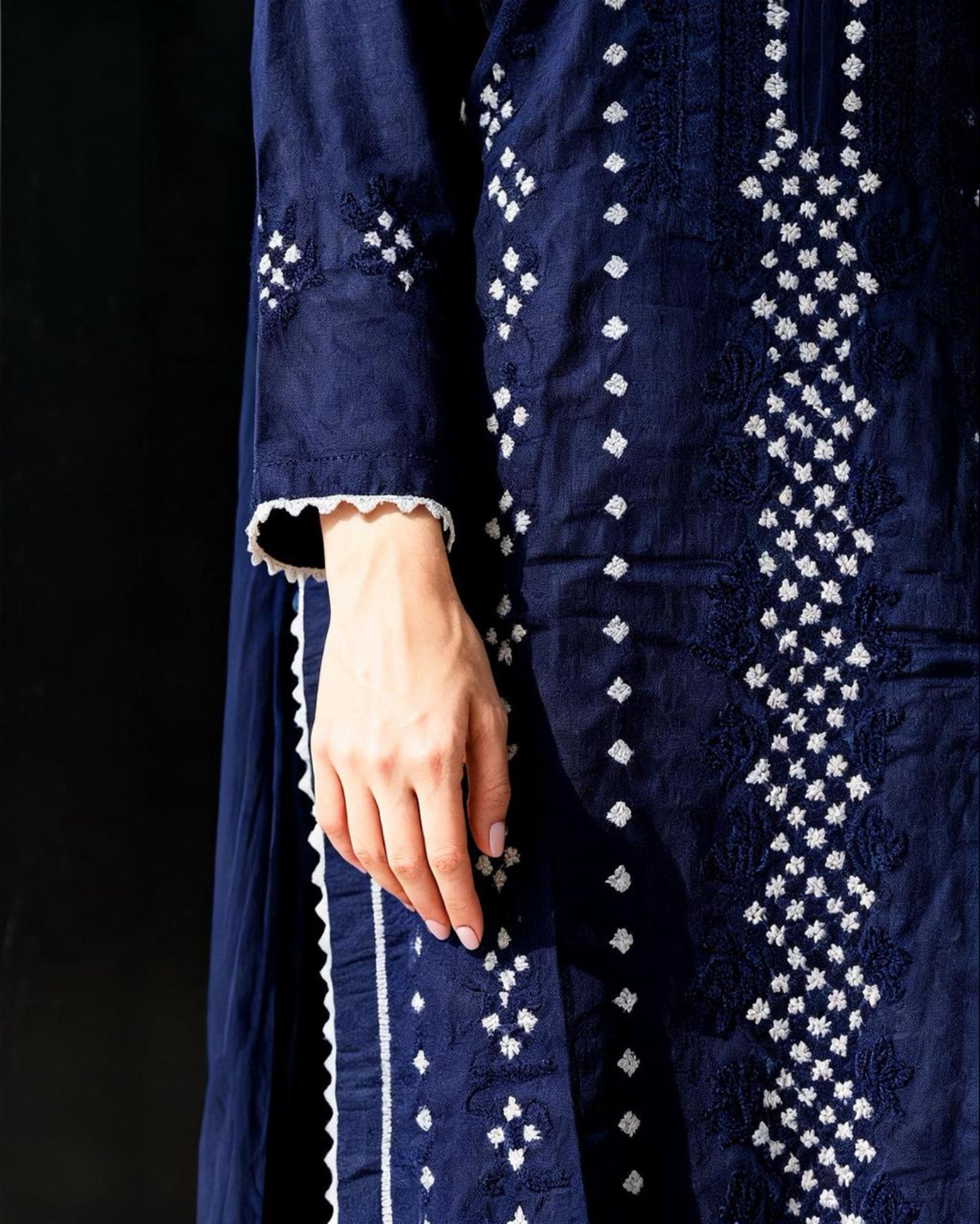 Navy blue embroidered garment with white patterns on a black background