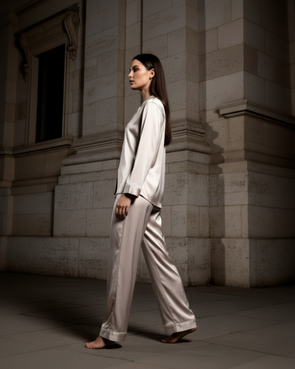 Woman in a light gray suit standing against a stone building.