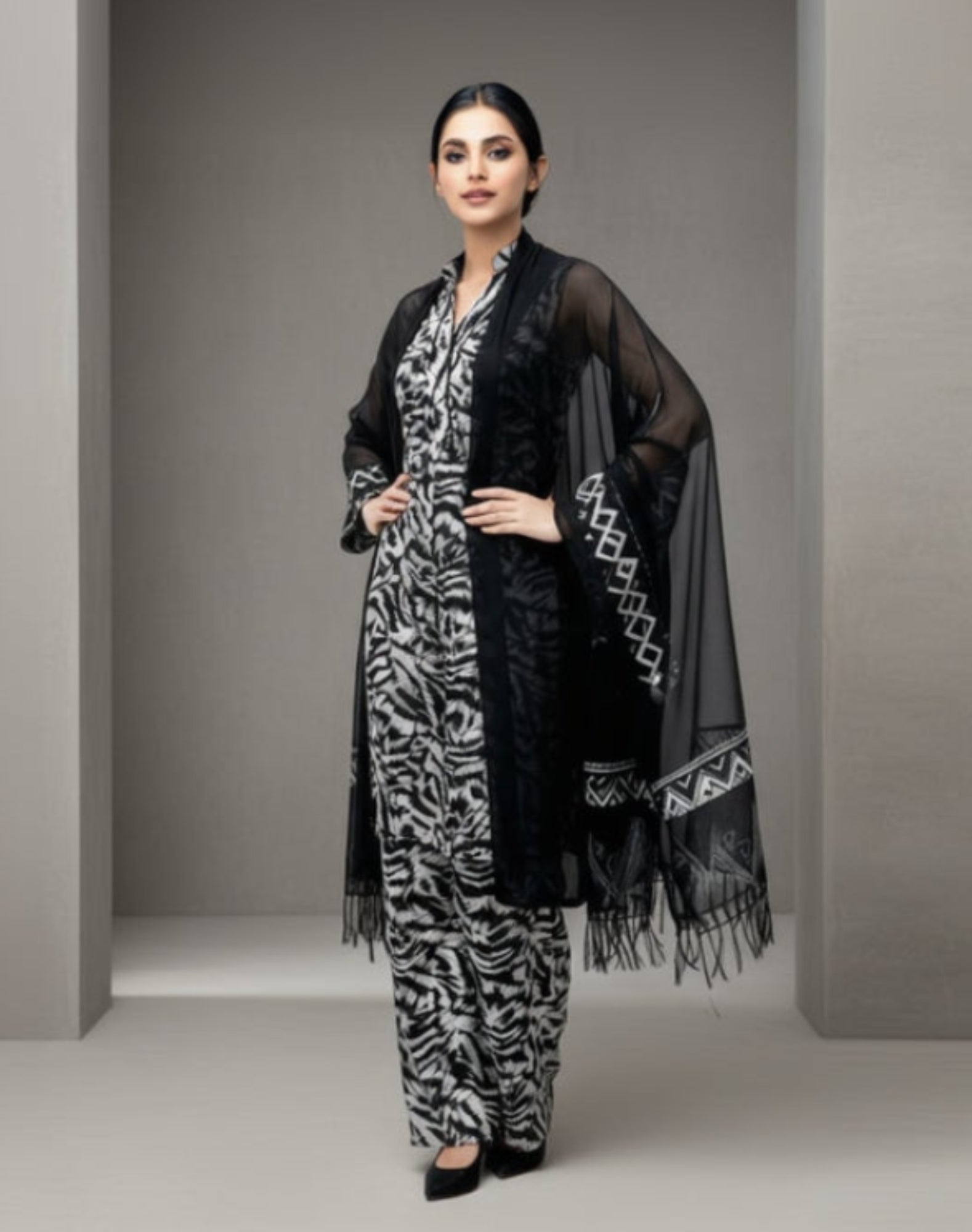 Woman wearing a black and white zebra print outfit with a matching shawl on a white background